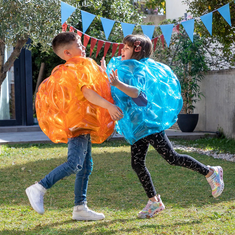 Zwei Personen spielen im Garten mit orangefarbenem und blauem Bumpoy Ball